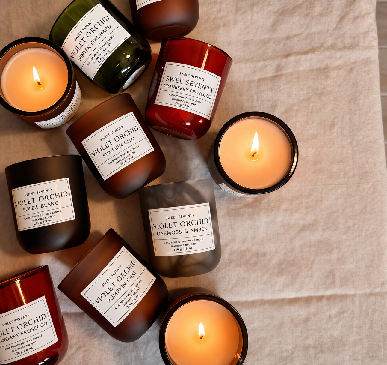 Collection of lit candles with labels on a textured surface